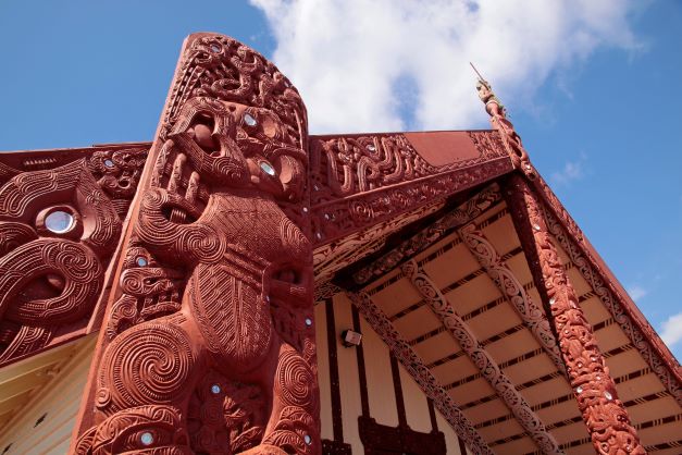 Holzschnitzereinen und Totem eines Begegnunghauses in einem Maori Dorf in Neuseeland.